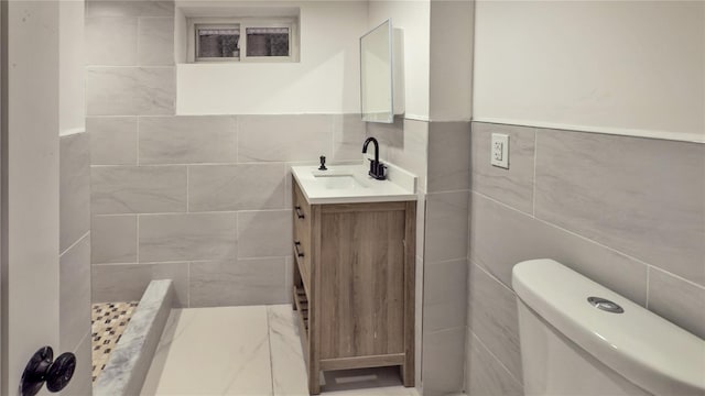 bathroom featuring vanity, toilet, and tile walls