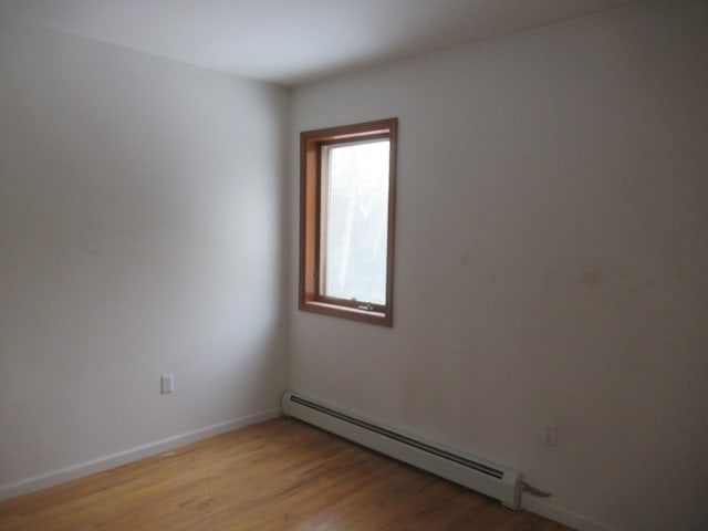 empty room with light hardwood / wood-style flooring and a baseboard heating unit