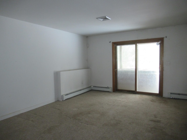 carpeted empty room with a baseboard heating unit