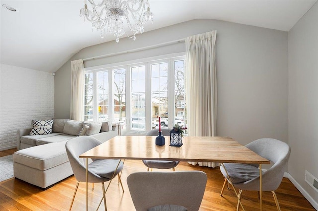 dining room featuring lofted ceiling, light wood-type flooring, and a notable chandelier