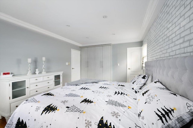 bedroom featuring crown molding, brick wall, and a closet