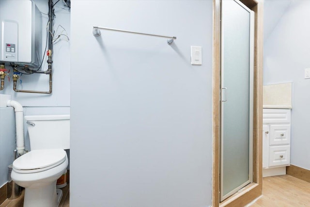 bathroom with wood-type flooring, a shower with shower door, tankless water heater, and toilet