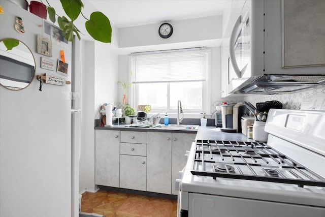 kitchen with light parquet floors, sink, gray cabinetry, and white appliances