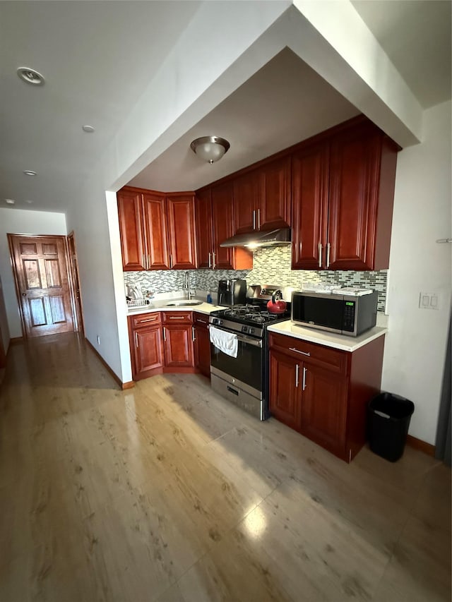 kitchen with tasteful backsplash, stainless steel appliances, sink, and light wood-type flooring