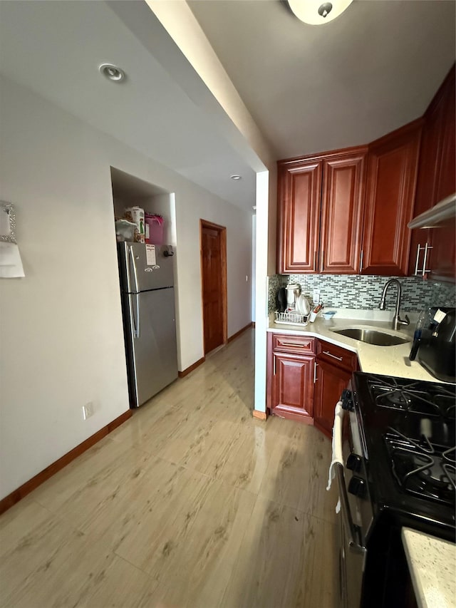 kitchen with sink, black range, stainless steel fridge, light hardwood / wood-style floors, and decorative backsplash