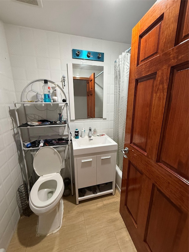 full bathroom with vanity, tile walls, shower / bath combo with shower curtain, and toilet