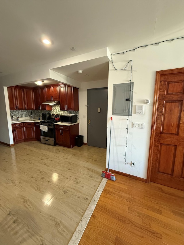 kitchen with backsplash, electric panel, light hardwood / wood-style floors, and appliances with stainless steel finishes