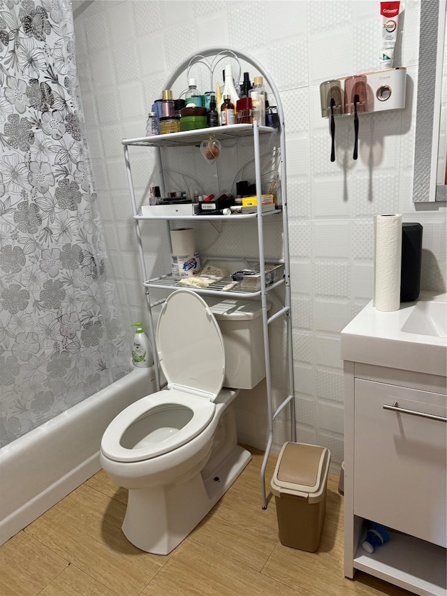 full bathroom with hardwood / wood-style flooring, vanity, shower / bathtub combination with curtain, and toilet