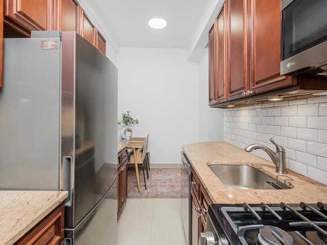 kitchen with light stone countertops, appliances with stainless steel finishes, sink, and backsplash