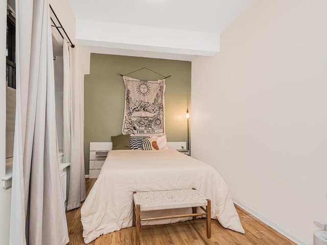 bedroom featuring wood-type flooring and beam ceiling