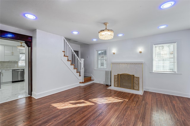 unfurnished living room featuring hardwood / wood-style floors, radiator heating unit, and a tile fireplace