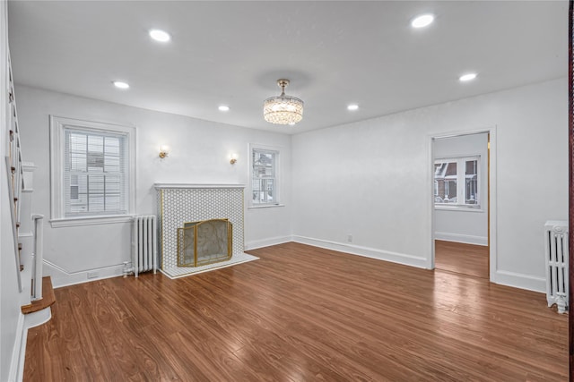 unfurnished living room featuring a tiled fireplace, radiator, and hardwood / wood-style flooring