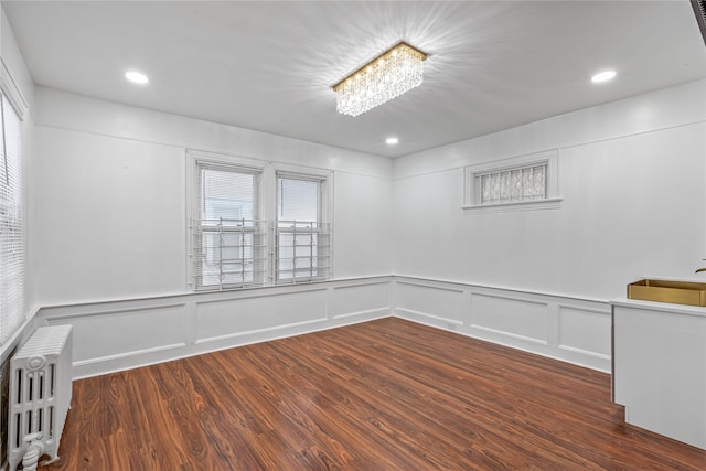 spare room featuring radiator, dark wood-type flooring, and plenty of natural light