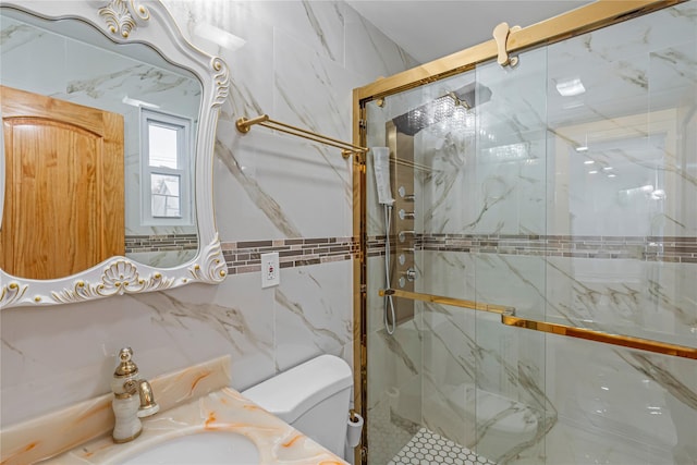 bathroom with a shower with door, vanity, tile walls, and toilet