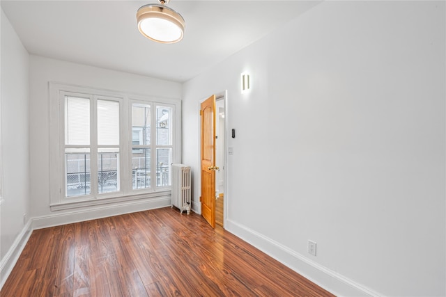 empty room featuring radiator and dark wood-type flooring