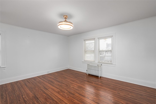 empty room featuring dark wood-type flooring and radiator heating unit