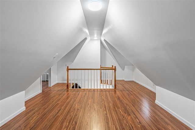 bonus room with lofted ceiling, dark hardwood / wood-style flooring, and radiator