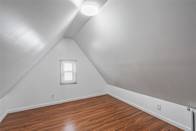 bonus room with vaulted ceiling and dark wood-type flooring