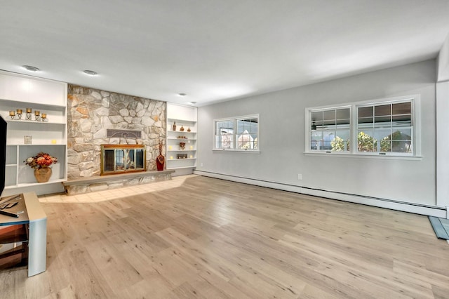 unfurnished living room with light hardwood / wood-style flooring, a stone fireplace, a baseboard radiator, and built in shelves