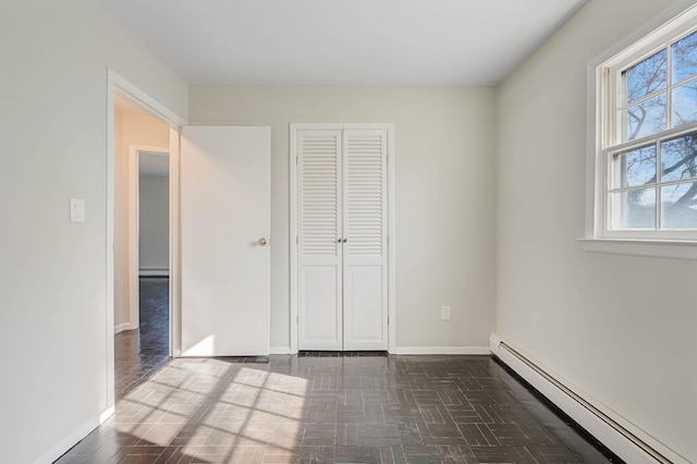 unfurnished bedroom with baseboard heating and a closet