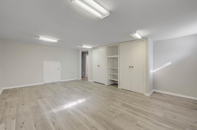 unfurnished bedroom featuring multiple closets and light wood-type flooring