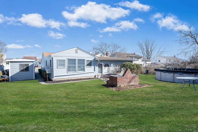 rear view of house with a covered pool and a yard