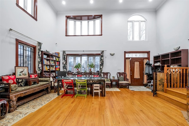 living room featuring hardwood / wood-style flooring, ornamental molding, and a high ceiling