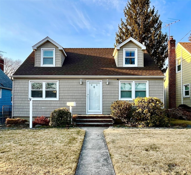 cape cod house with a front lawn and roof with shingles