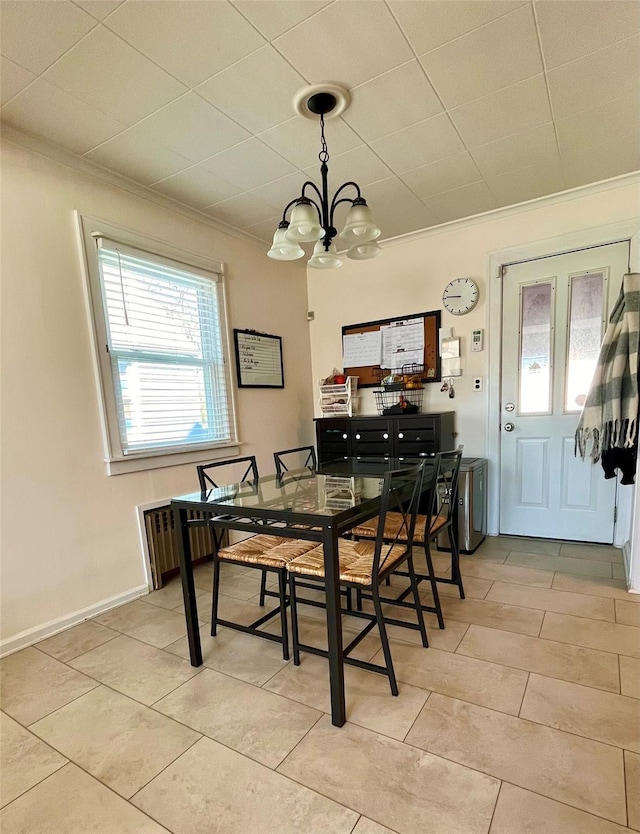 dining space with light tile patterned floors, baseboards, an inviting chandelier, and ornamental molding