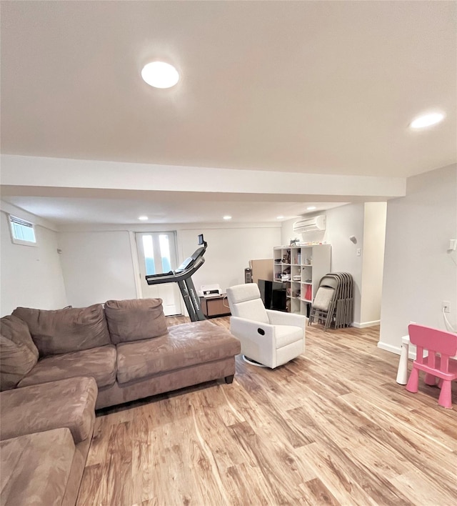 living room featuring recessed lighting, an AC wall unit, light wood-type flooring, and baseboards