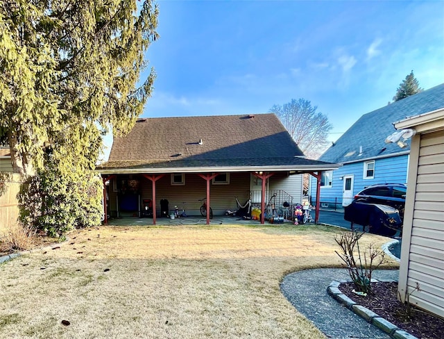 rear view of property featuring a yard and roof with shingles