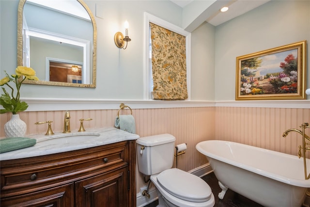 bathroom featuring toilet, vanity, and a bath