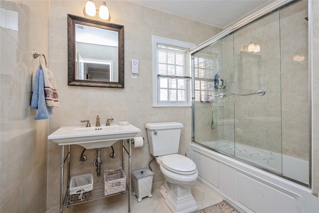 full bathroom with tile patterned floors, enclosed tub / shower combo, sink, toilet, and tile walls