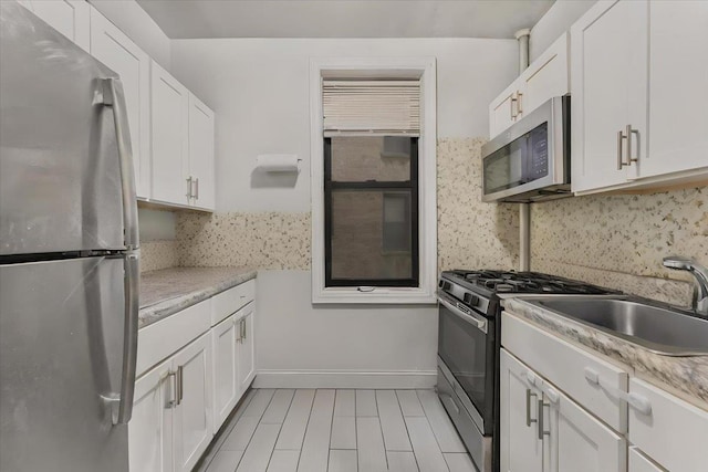 kitchen with light stone countertops, white cabinetry, and appliances with stainless steel finishes