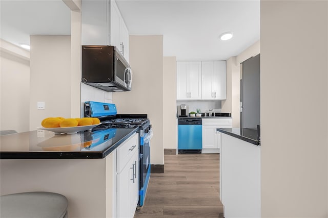 kitchen featuring dark countertops, appliances with stainless steel finishes, white cabinetry, and wood finished floors