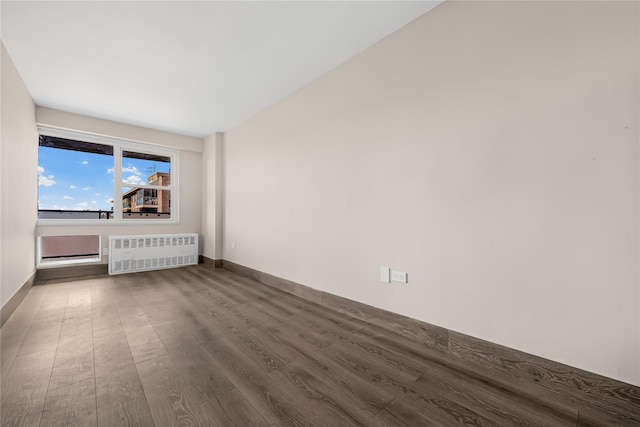 spare room with radiator heating unit, baseboards, and dark wood-style flooring