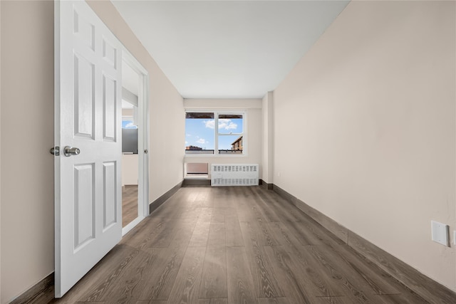 corridor featuring baseboards, radiator, and dark wood finished floors