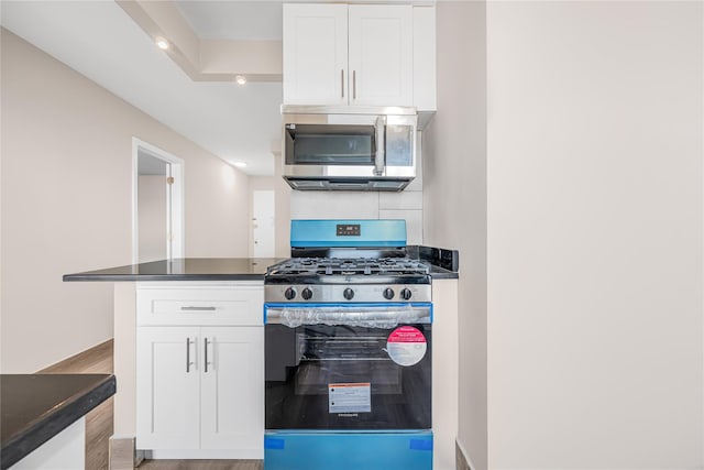 kitchen with stainless steel appliances, dark countertops, and white cabinets