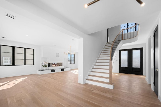 interior space featuring french doors, a multi sided fireplace, a chandelier, and light hardwood / wood-style flooring