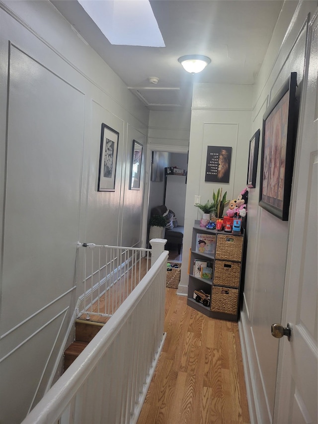 corridor featuring light wood-type flooring and a skylight