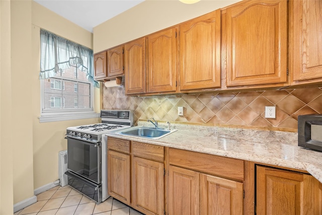 kitchen featuring light tile patterned flooring, sink, range with gas cooktop, tasteful backsplash, and light stone countertops