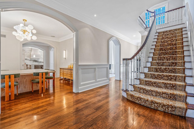 foyer entrance with arched walkways, crown molding, and hardwood / wood-style flooring