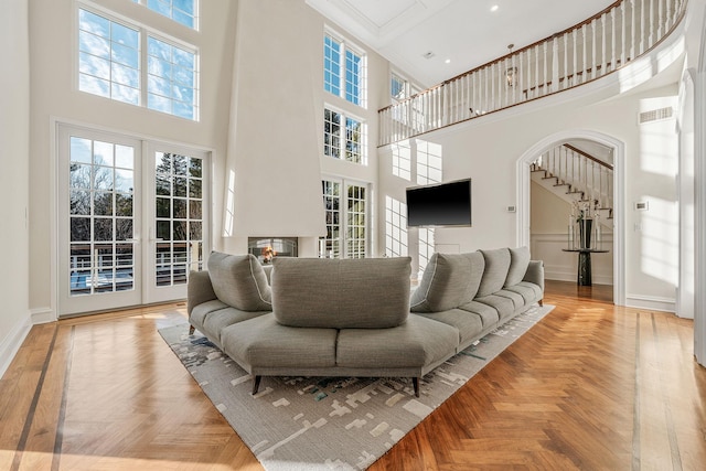 living room featuring arched walkways, visible vents, baseboards, french doors, and a glass covered fireplace