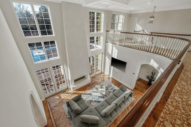 living room with ornamental molding, beam ceiling, coffered ceiling, and a towering ceiling