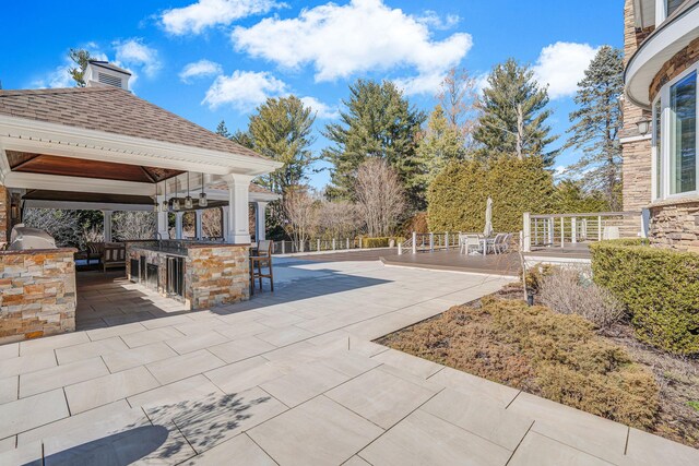 view of patio with outdoor dry bar, a gazebo, and area for grilling