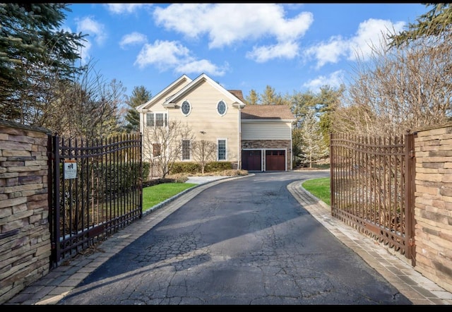 view of front of property featuring aphalt driveway, a gate, fence, and a garage