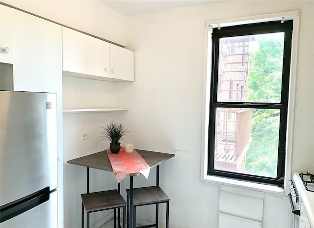 kitchen with white cabinetry, a healthy amount of sunlight, a breakfast bar area, and stainless steel fridge