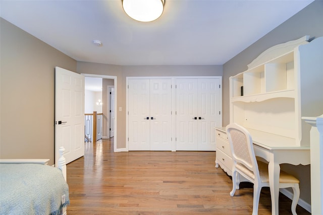 bedroom with light hardwood / wood-style flooring and multiple closets