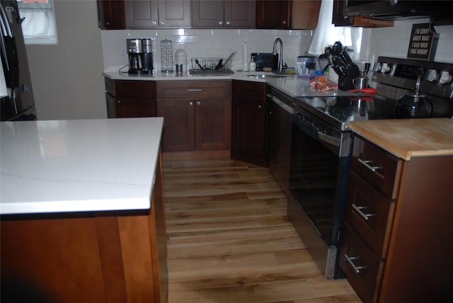 kitchen featuring sink, light hardwood / wood-style flooring, dishwasher, stainless steel electric stove, and backsplash