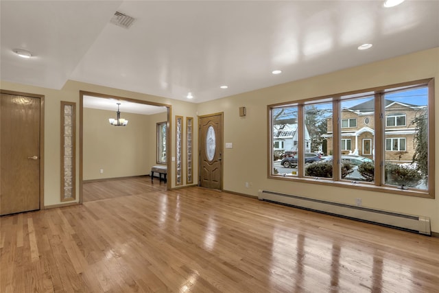 entrance foyer with a baseboard radiator, a notable chandelier, and light wood-type flooring